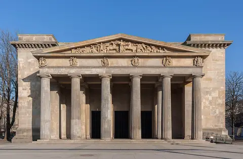 A small classical building with a Doric portico and a sculpted pediment under a clear blue sky
