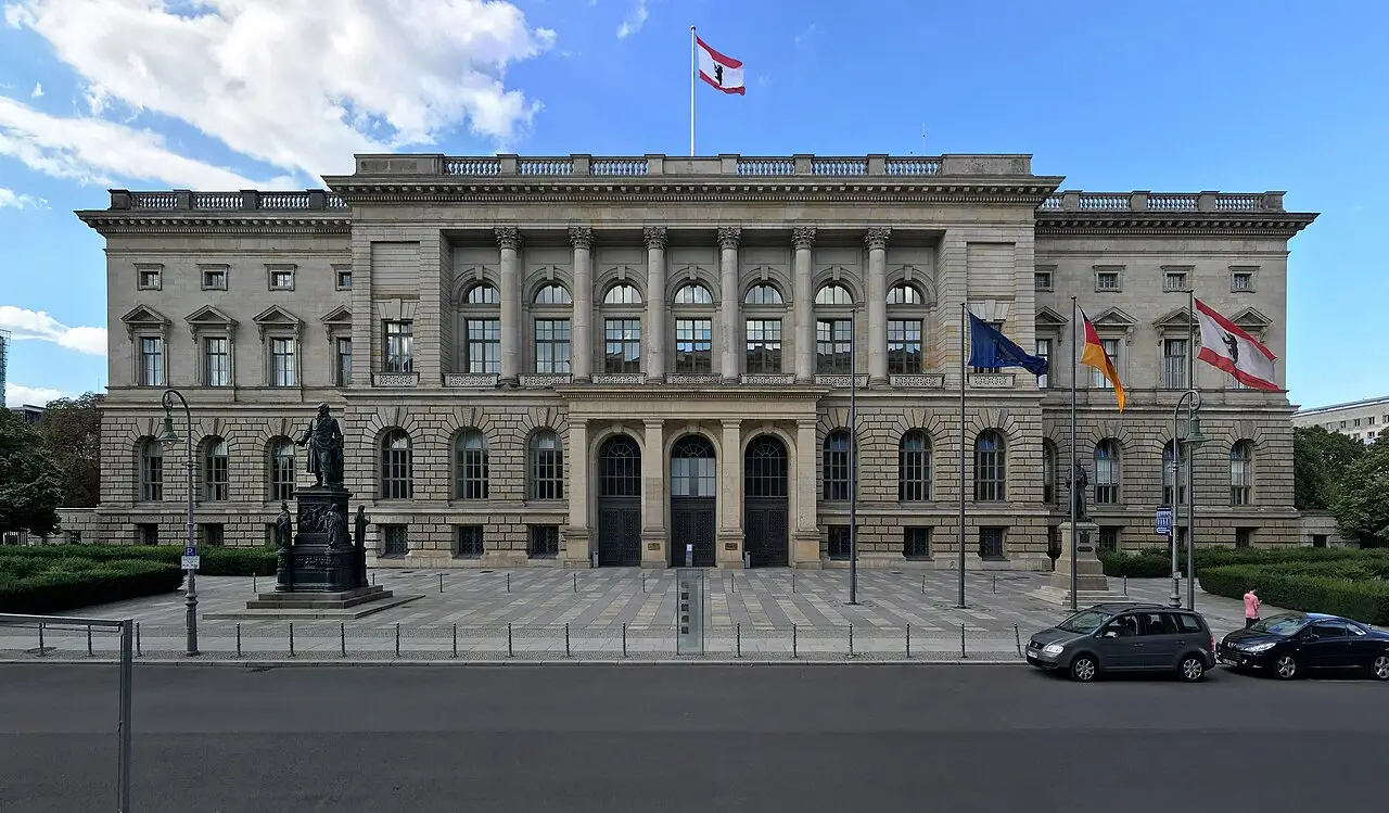 A large neo-Renaissance stone parliament building behind a lawn