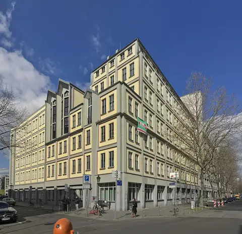 A pale six-storey office building on a street corner, its front divided into a grid by its concrete frame