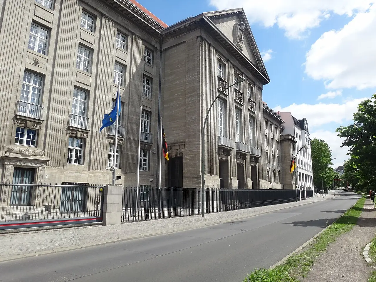 A long pale stone building with rows of windows behind a street