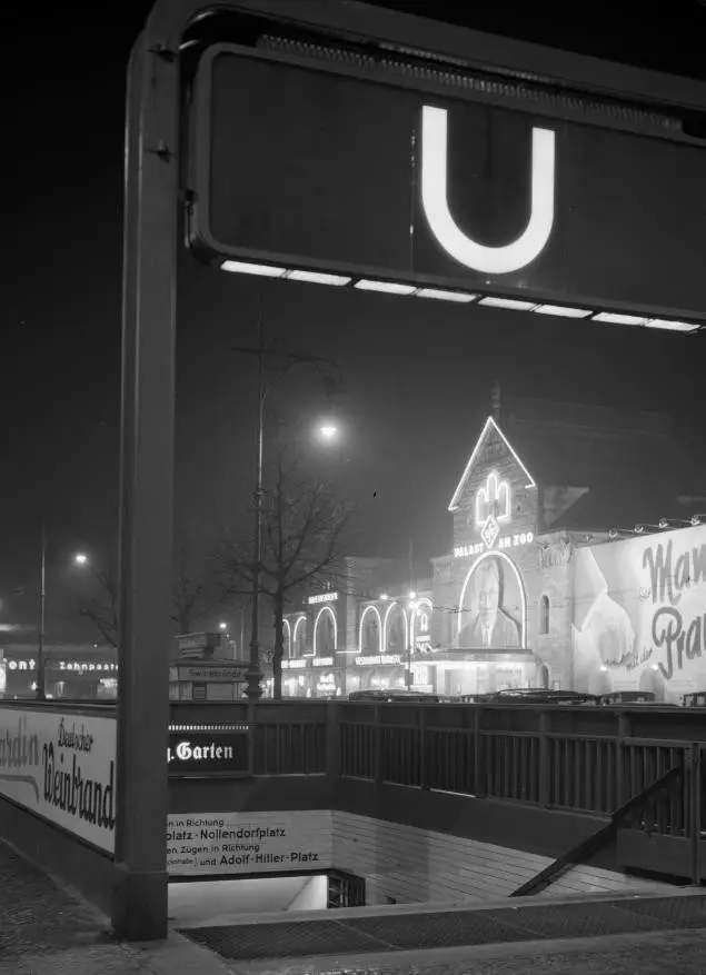 A brightly lit cinema and café façade on a city street at night