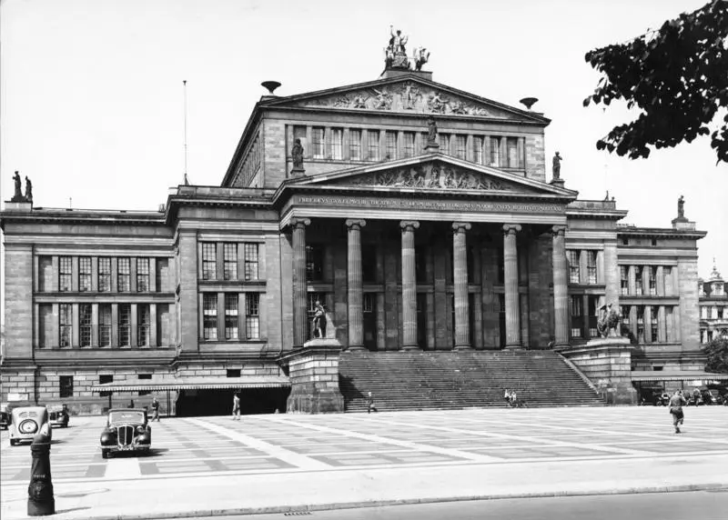 A neoclassical theatre with a columned portico and broad steps, seen across a square.