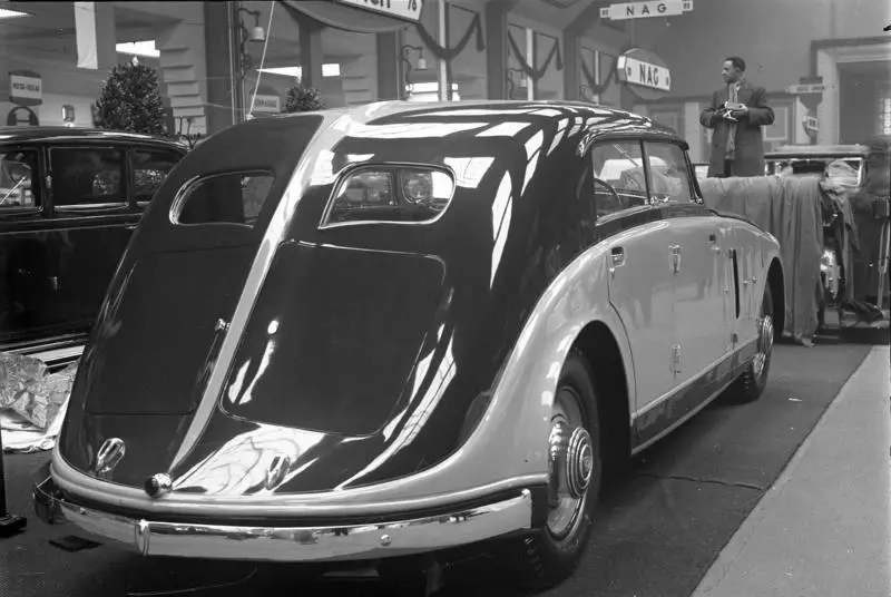A large streamlined luxury car on display in an exhibition hall
