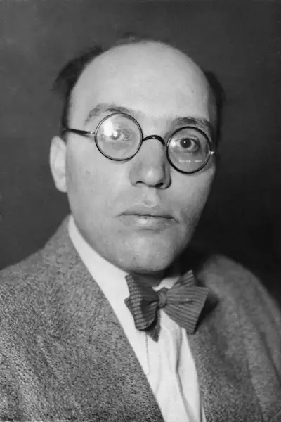 Portrait of a balding man with round glasses and a patterned bow tie.