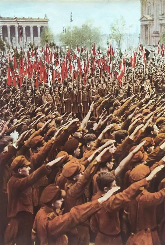 Rows of boys in uniform giving the Nazi salute with flags behind them