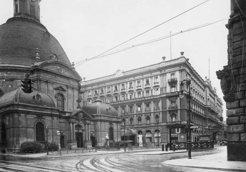 A large corner hotel building with a long facade on a city square