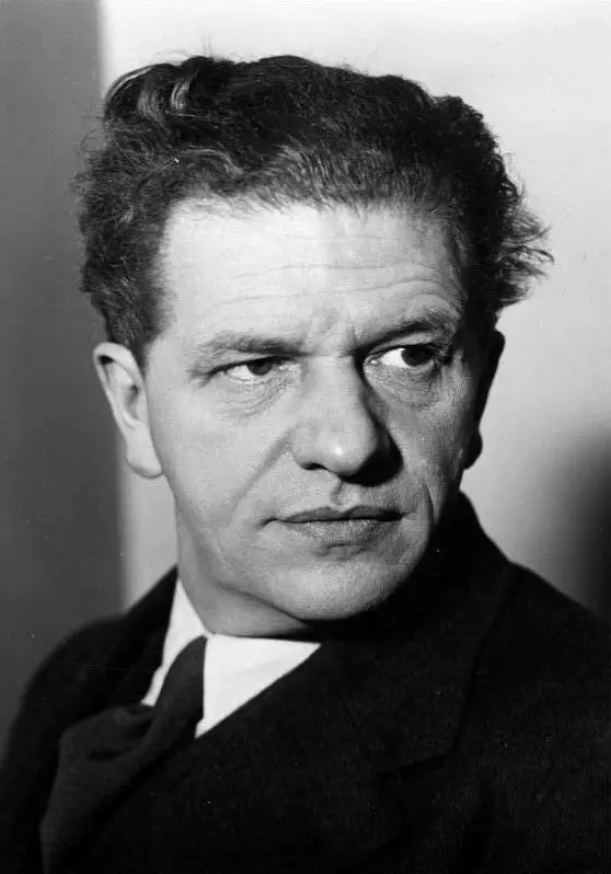 Portrait of a man with swept-back hair in a dark suit and tie.