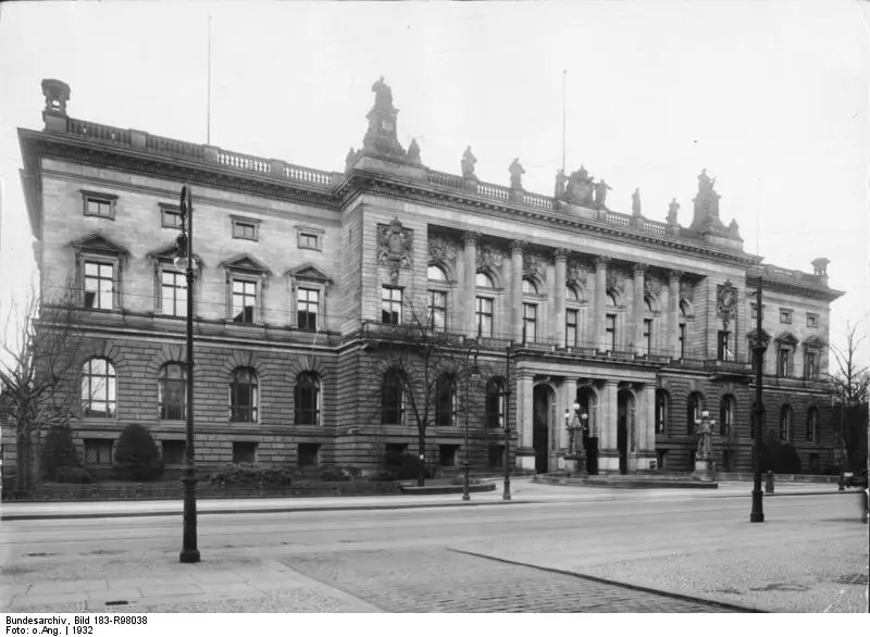 A long neo-Renaissance parliament building with a sculpted central gable, seen across an empty street