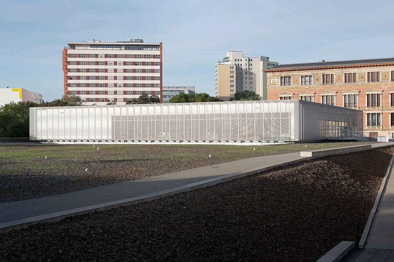 A long low modern building with a grey metal screen facade surrounded by gravel