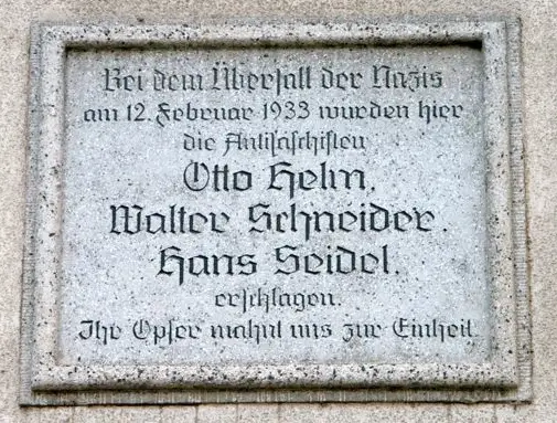 A stone plaque with an engraved inscription naming three men
