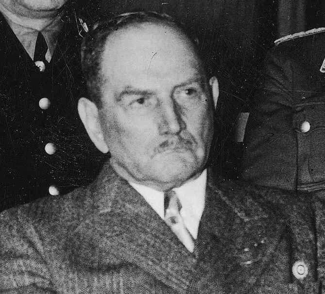Head-and-shoulders photograph of an elderly man with a moustache, wearing a tweed jacket and tie.