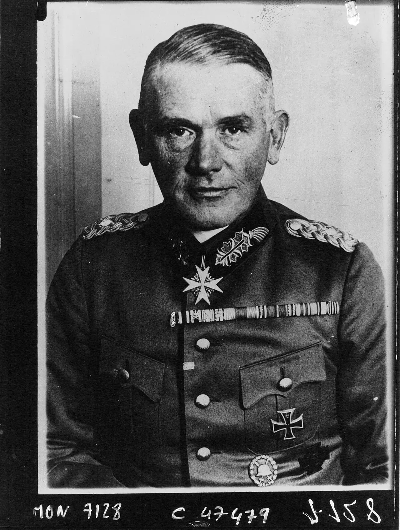 Portrait of a grey-haired officer in a high-collared uniform tunic with an order at his throat and an Iron Cross on his breast