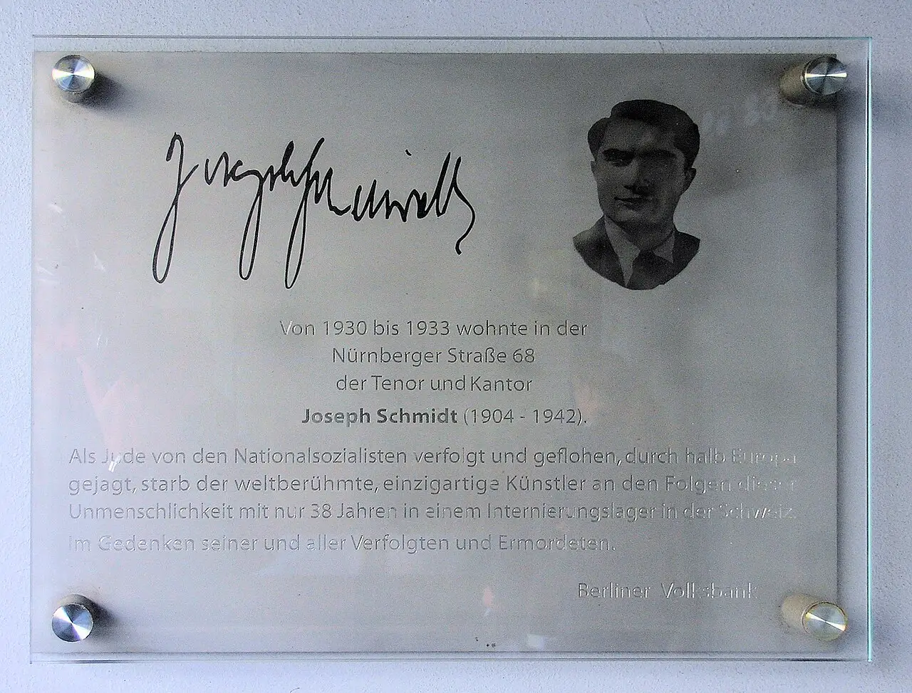 A glass-mounted metal plaque with a signature, a small portrait of a young man and an inscription