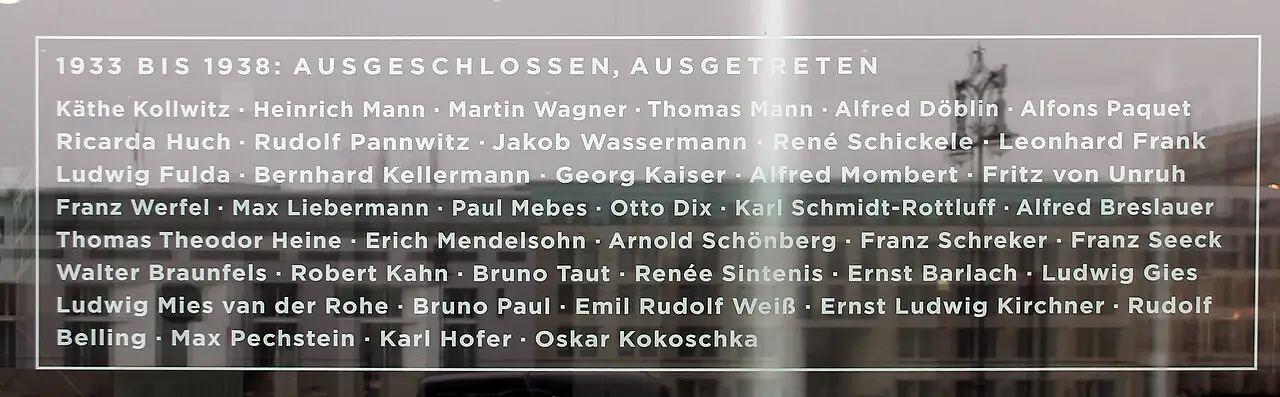 A long glass plaque with white lettering listing several dozen names under a heading