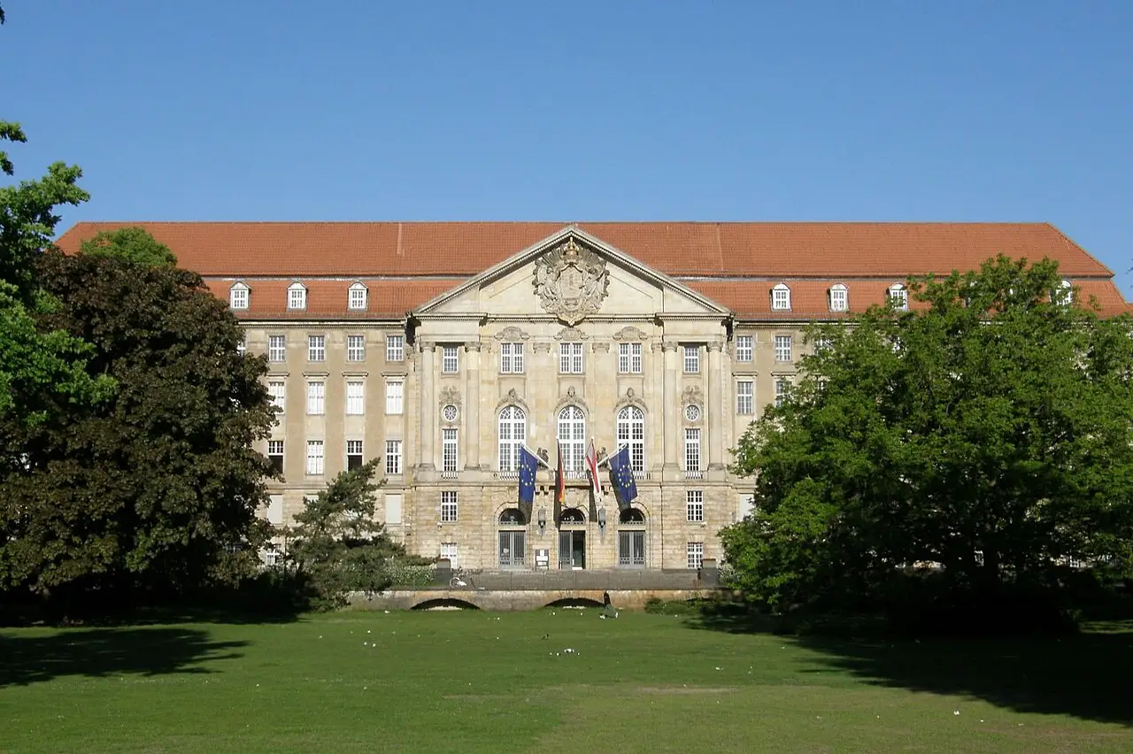 The grey stone façade of the Kammergericht behind trees and lawns of the Kleistpark.