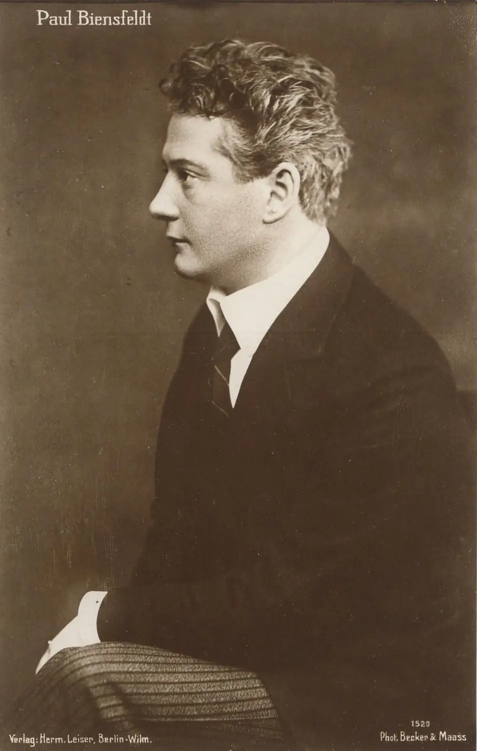 Studio portrait of a middle-aged man with a round face in a dark jacket.