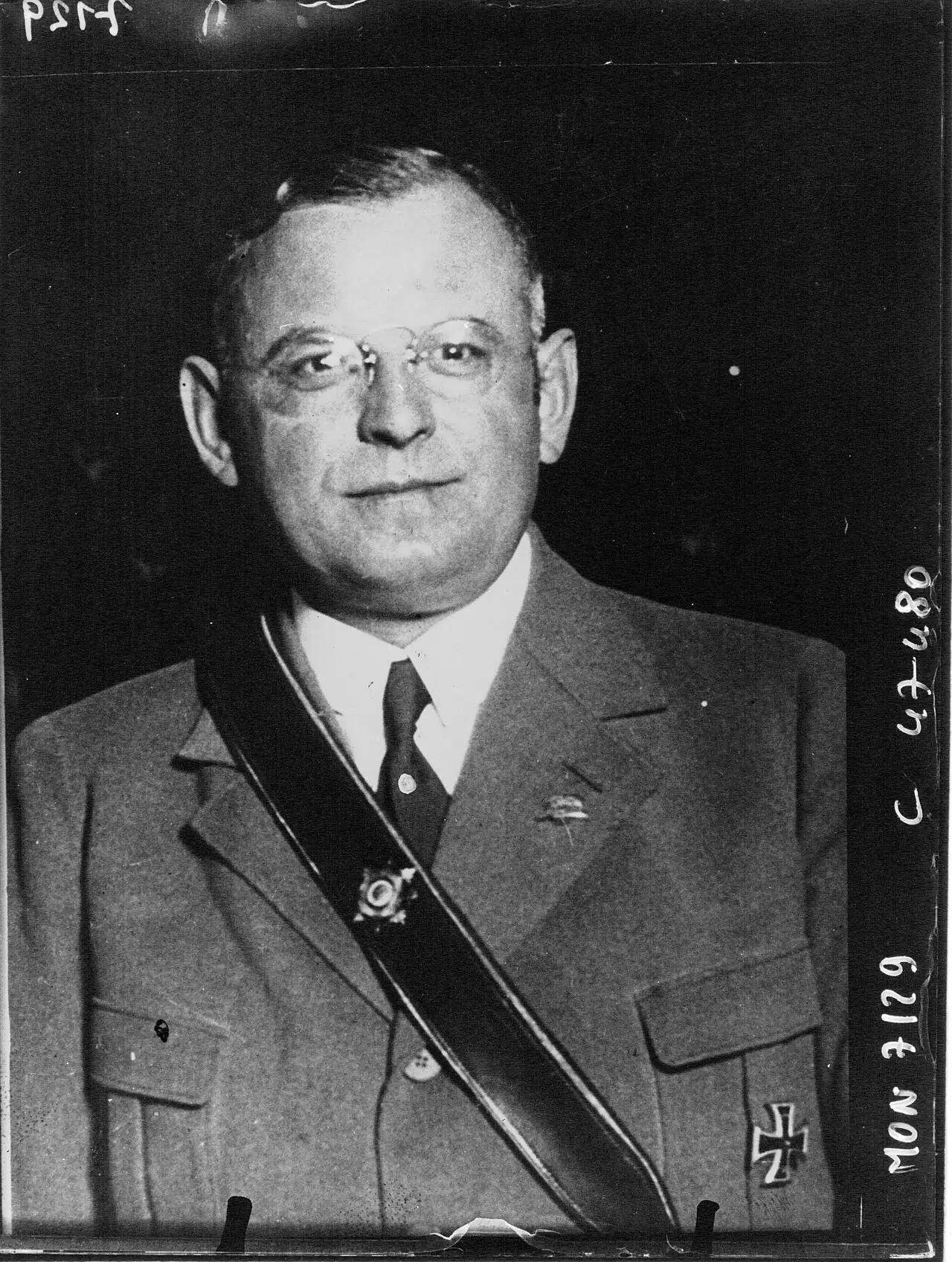 Portrait of a man in glasses wearing a uniform jacket with a cross-strap and an Iron Cross