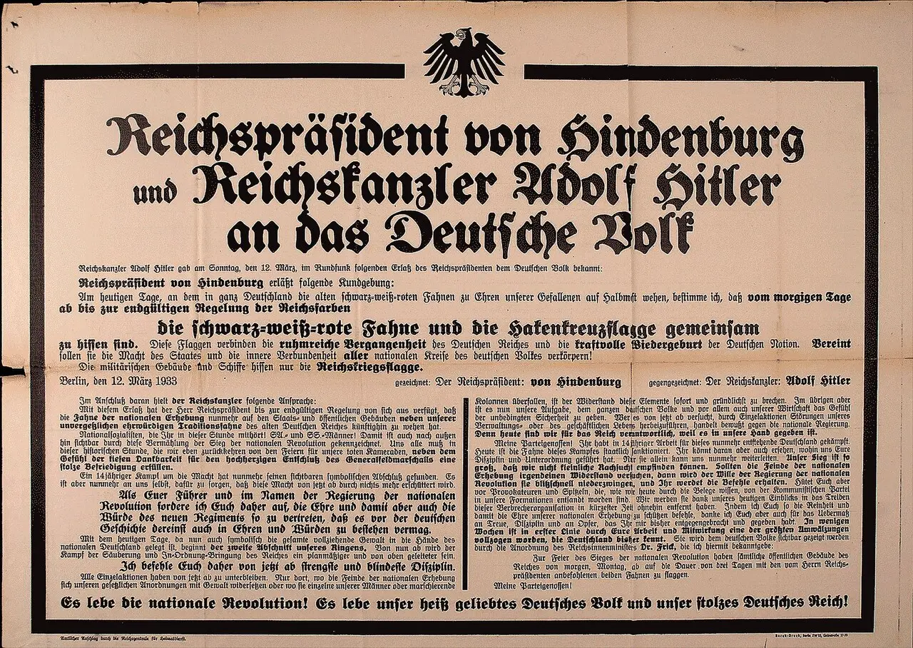 A wide printed poster in black Gothic type under an eagle emblem, with a large headline and two columns of text, framed by a black border.