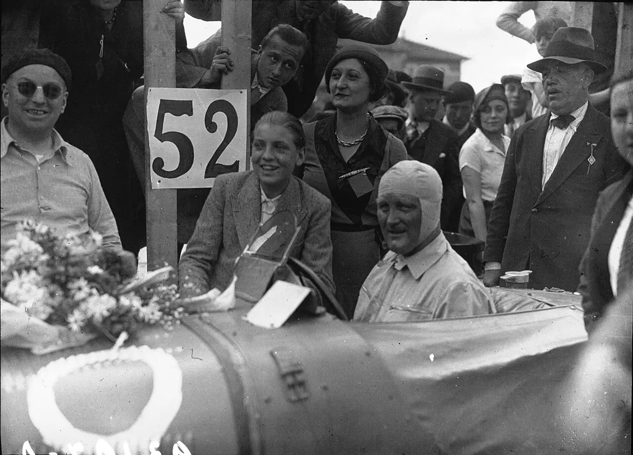 A racing driver in goggles sitting in an open single-seat racing car