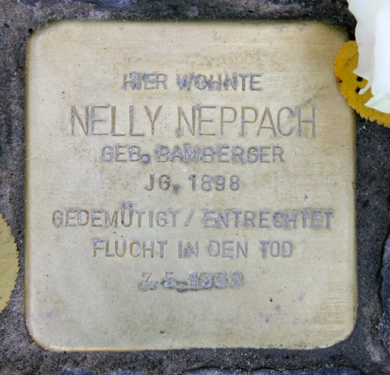 A small brass plaque set into paving stones, engraved with Nelly Neppach's name and dates