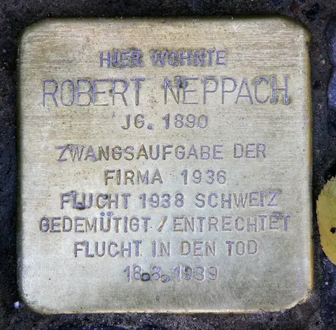 A small square brass plaque set in paving, engraved with Robert Neppach's name and dates